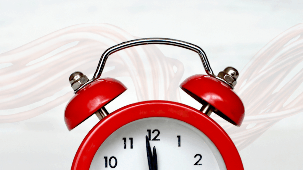 A red alarm clock shows the time near midnight while faded copper wires trail behind it—a visual reminder that the phase-out of Plain Old Telephone Service (POTS) phone lines is here.