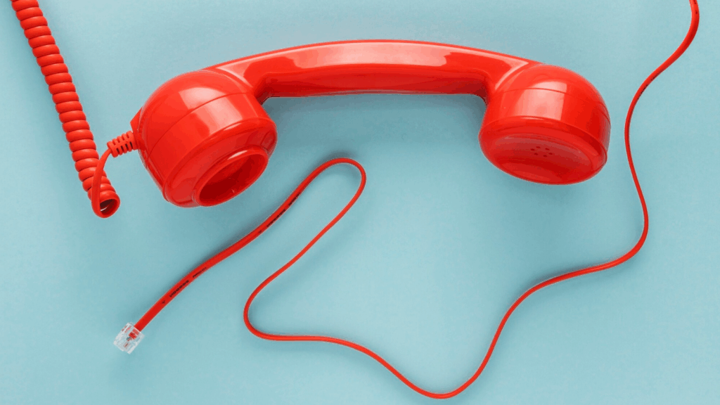 Red vintage-style telephone handset with cord, representing POTS replacement, on a light blue background.