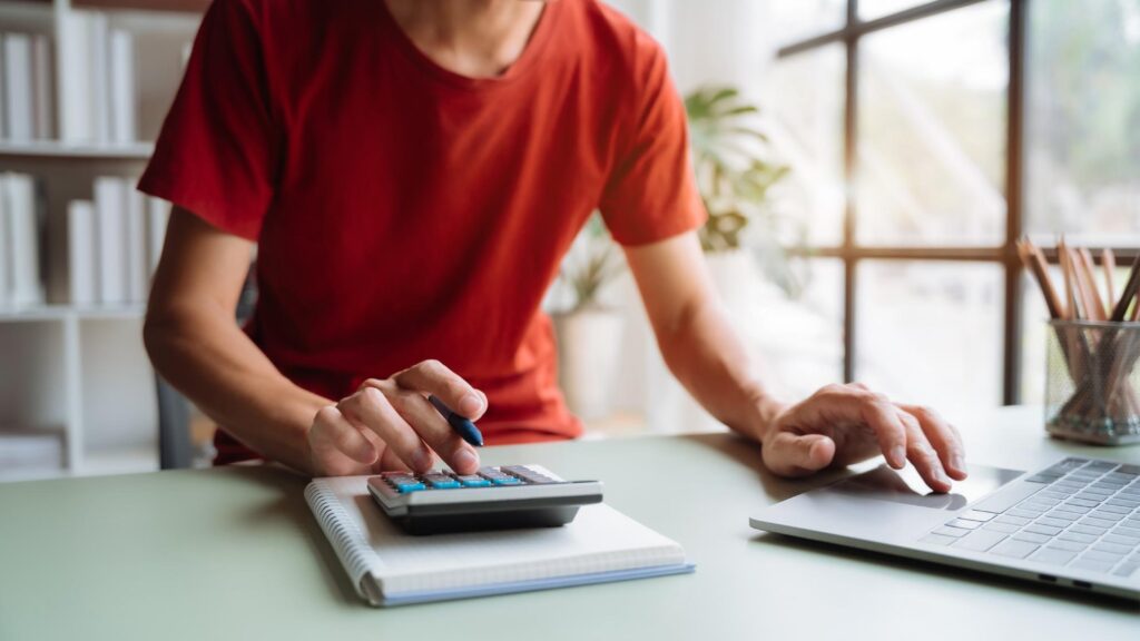 A person reviewing their telecom bills with a calculator, employing the 5 telecom cost optimization tips here.